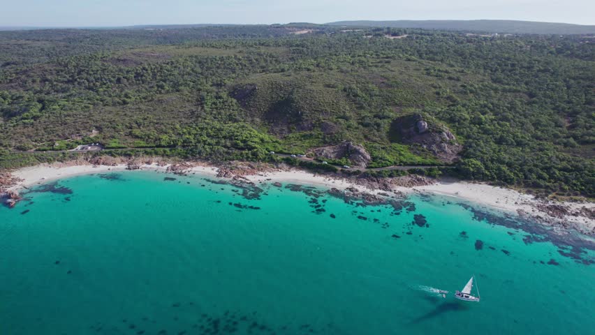 Aerial view of yacht passing by with coastline and road in the background with cars driving past at Eagle Bay Western Australia