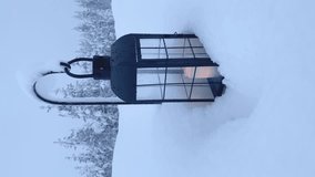 Vertical. A lantern with a burning candle in a snowdrift sways in the wind - Powered by Shutterstock - Get 15% off with code: PIKWIZARD15