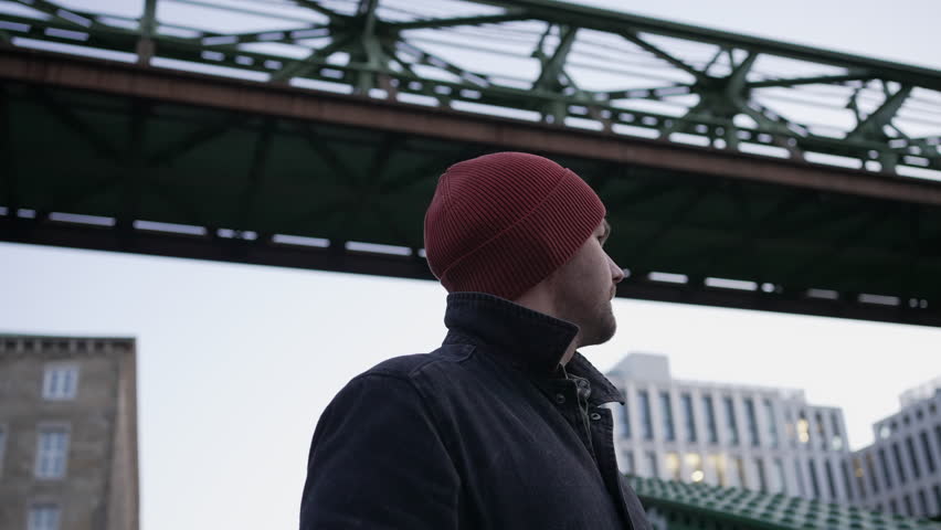 Solitary man wandering in WUPPERTAL gazing at suspended train passing by, Germany