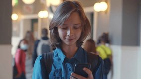 Teenage boy use smartphone at school. Realtime. High school student with mobile phone at school corridor. Portrait of smiling caucasian schoolboy use cellphone. Realtime - Powered by Shutterstock - Get 15% off with code: PIKWIZARD15