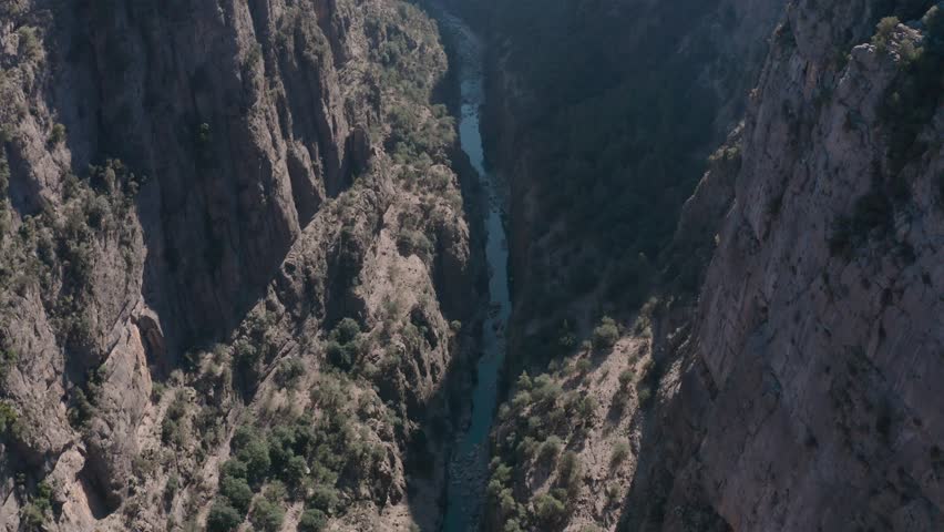 Drone panning up to reveal a huge canyon with a river running through