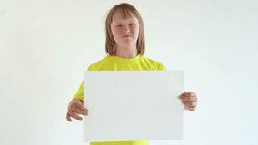 A teenage girl with blond hair in a yellow T-shirt holds a sheet of A3 paper and smiles. mock up and space for text, Down syndrome awareness concept. International Down Syndrome Day. - Powered by Shutterstock - Get 15% off with code: PIKWIZARD15