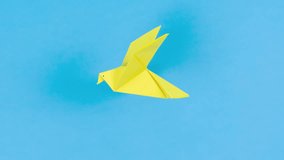 4k Yellow paper transforms into an origami dove that flies. Symbol of peace. Blue background. Concept of help, support and peace for Ukraine in fight against Russian aggression. Stop motion animation. - Powered by Shutterstock - Get 15% off with code: PIKWIZARD15