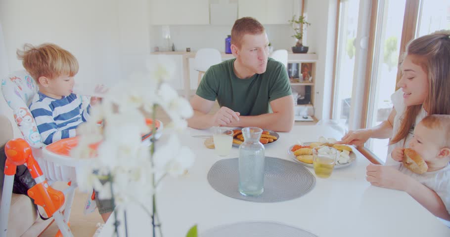 Parents talking while eating with their kids at the dining table in the dining room