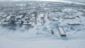 Industrial town on river bank in winter. Clip. Top view of town with marine industry near river bank. Marine industrial town by river on sunny winter day