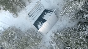 Top view of construction site of house in forest in winter. Clip. House under construction in dense coniferous forest in winter. Construction of single house in wilderness in winter