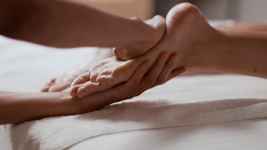 Body relaxation and skin care. Close up shot of young woman getting leg and feet massage in resort spa salon, unrecognizable masseur rubbing female foot, slow motion Royalty-Free Stock Footage #1100653913