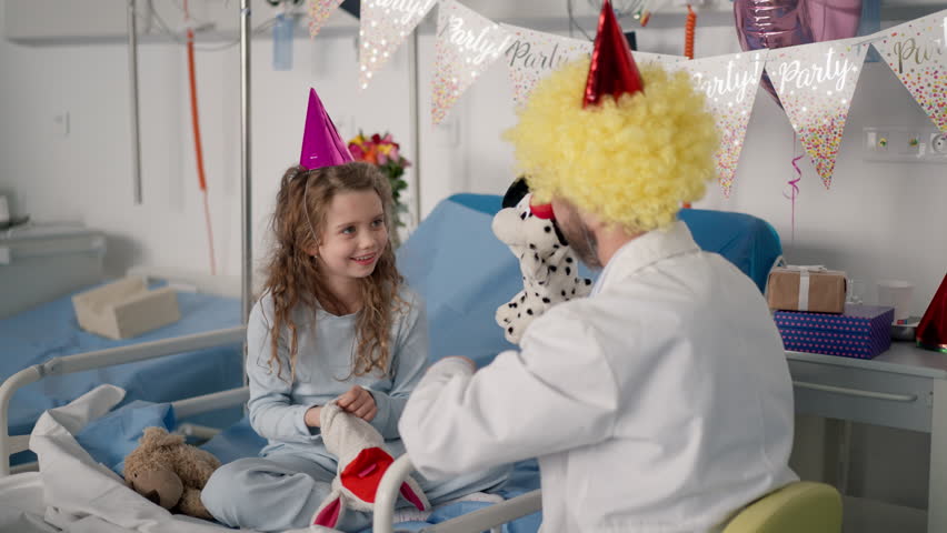 Happy doctor with clown red noses celebrating birthday with little girl in hospital room. Royalty-Free Stock Footage #1100654529
