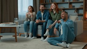 Four diverse ethnicity friends watch television at home cinema people spectators watching smart tv channel comedy show serial movie multiracial african american caucasian women men laughing enjoy film