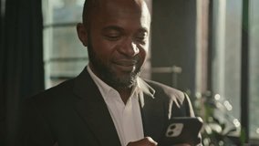 Adult entrepreneur African American businessman ethnic mature man standing in sun sunbeams corporate office use mobile phone texting message online. Close up camera shooting male hands hold smartphone - Powered by Shutterstock - Get 15% off with code: PIKWIZARD15