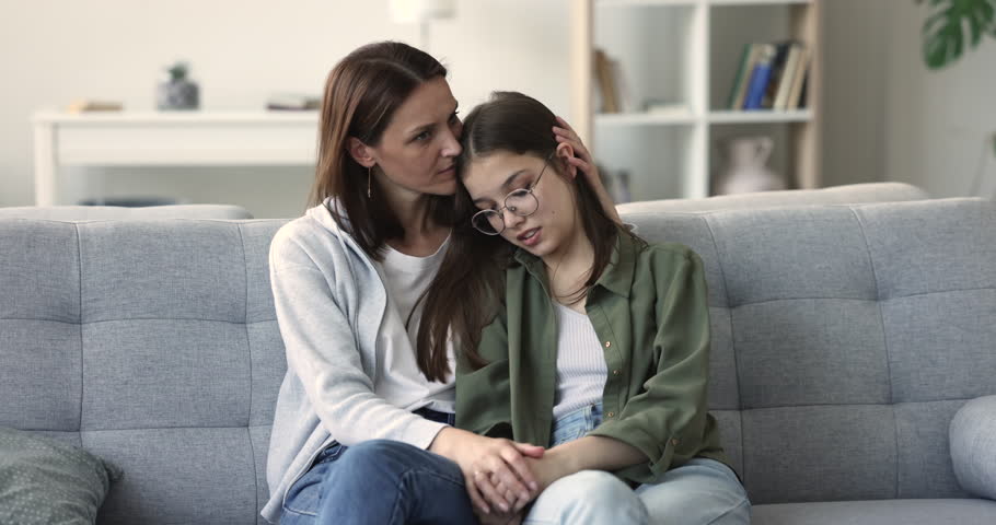 Sad teenager girl talks to caring caressing mother. Loving mature mum, soothes her adolescent daughter, express support, touch, strokes hair, give advice to concerned child. Motherhood, teen problems | Shutterstock HD Video #1100656553
