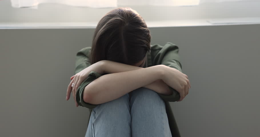Close up unhappy teen girl hiding face put head on laps sit alone leaned on wall, feels hopeless, crying, suffers from bullying in school, grieving, goes through nervous breakdown, psychological abuse Royalty-Free Stock Footage #1100656561