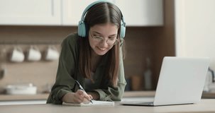Pretty teenager in headphones take part in class with tutor or schoolmate prepare common task, talking, take notes, make exercise with help of on-line teacher. Education, videocall, e-learn, tuition