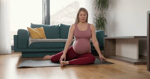 Young pregnant woman doing mobility exercise at home in the morning.