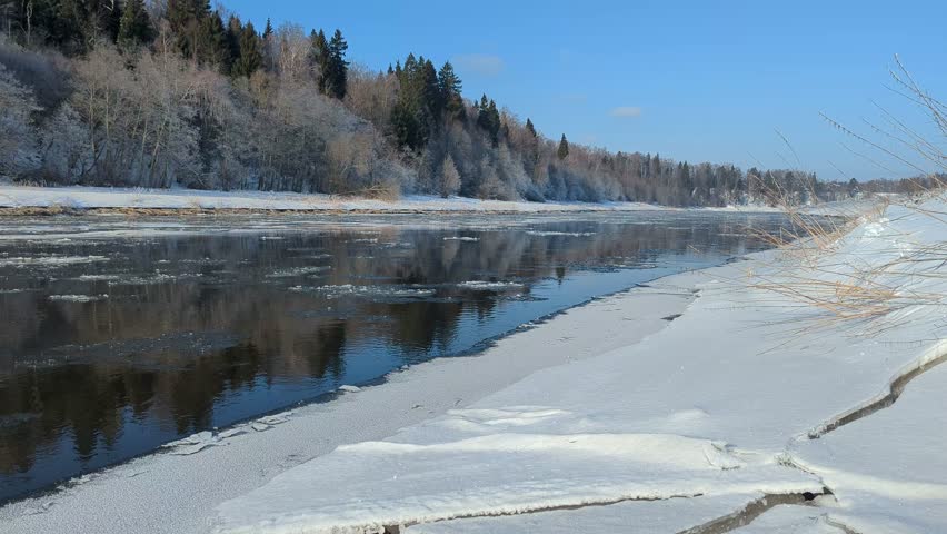 Ice floats, moves along the river, ice drift, winter landscape, river in the forest.