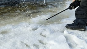 A child with a stick hammers the melted ice and snow on the river. Legs and arms close-up. - Powered by Shutterstock - Get 15% off with code: PIKWIZARD15