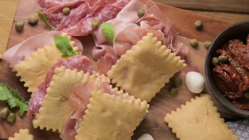 Crescentina. Food of Emilia Romagna region, deep fried bread gnocco fritto or crescentina. Starter or aperitif in Italy. Creshantina with prosciutto crudo, mortadella, Milanese salami, capers, cheese 