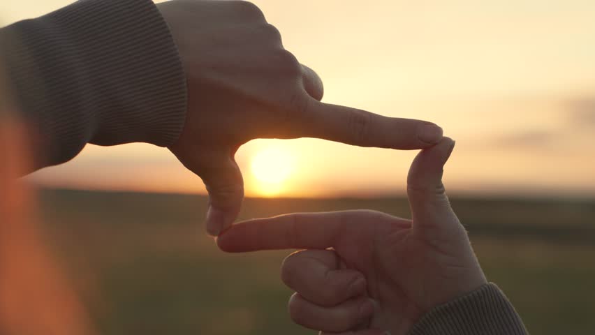 Business planning. Sees like in movies. Concept of seeing world as different. Hands of young female director cameraman making frame gesture at sunset in park.Girl shows her fingers frame symbol, sun | Shutterstock HD Video #1100663213