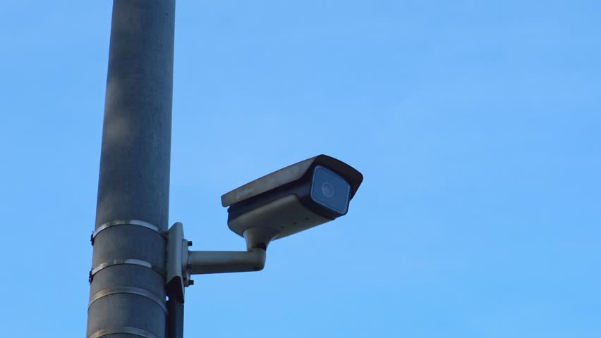 Close-up Of Security Camera On The Street. Focus on security CCTV camera monitoring system with panoramic view of blu sky