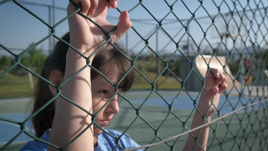 Restriction of the freedom of the child. Sad little girl behind an iron grid.