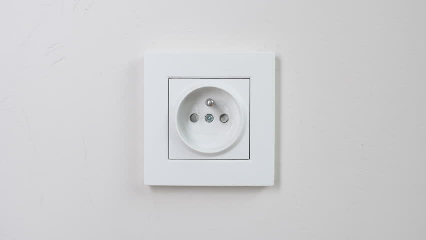 Male hand plugging and unplugging plug into white wall socket. Close-up power socket, caucasian man, charger cable