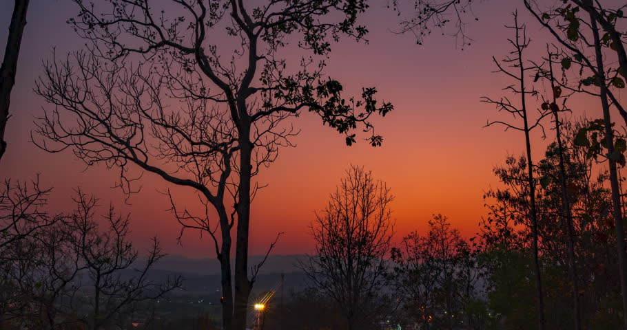 Time lapse day to night from sunset to night with the stars and moon over the town view from the forest in northern Thailand. The clip has the slowly Dolly zoom effect.