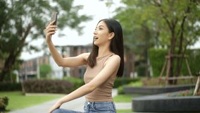 Happy feeling of beautiful young woman video calling looking at camera. Blogger enjoy online conversation. Vlogger or influencer female holding smartphone selfie talking to camera shooting vlog. 