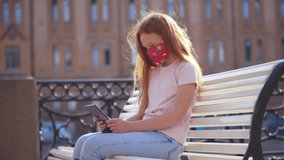 Teen girl in medical mask use digital tablet outdoors. Teenage kid sit on bench with tablet pc wearing protective mask during covid-19 pandemic. Schoolgirl use tablet in city. Realtime.  - Powered by Shutterstock - Get 15% off with code: PIKWIZARD15