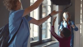 Mean teen boys i mask throw backpack of African-American classmate. High school students in protective mask bully boy throwing his bag at school. School bullying concept. Realtime.  - Powered by Shutterstock - Get 15% off with code: PIKWIZARD15