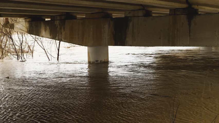 Flooding. Water in the river rose to the top of the car bridge. Concrete pillars under water. Muddy river after heavy rain. Natural disasters. A weather disaster. Environmental disaster