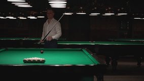 a man in a white shirt plays Russian billiards, starts the game. breaks the pyramid playing Russian billiards. slow motion video. High-quality video recording in Full HD.