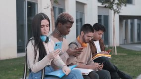 Multiracial group of friends using the mobile sitting in a park