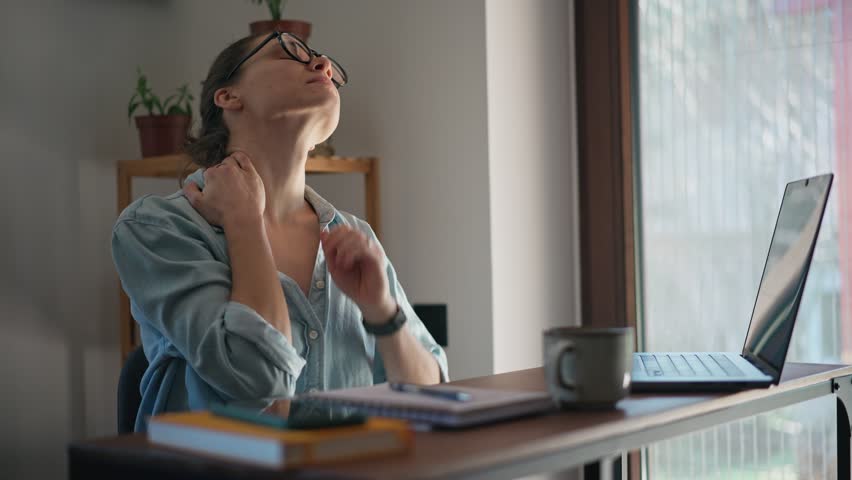 Tired young business woman massaging her neck and taking a break from working on laptop at the home office. Royalty-Free Stock Footage #1100682015