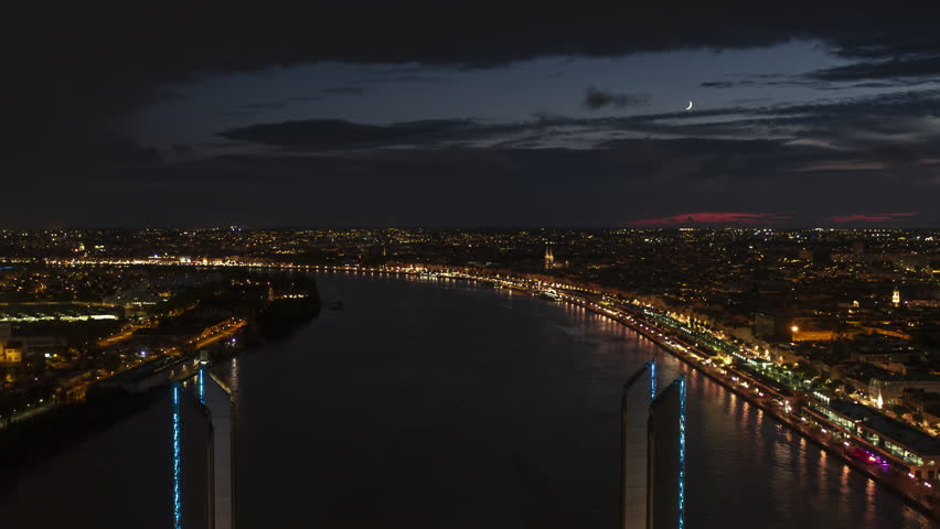 Establishing Aerial View Shot of Bordeaux Fr, world capital of wine, Nouvelle-Aquitaine, France at night, evening, track back, modern bridge
