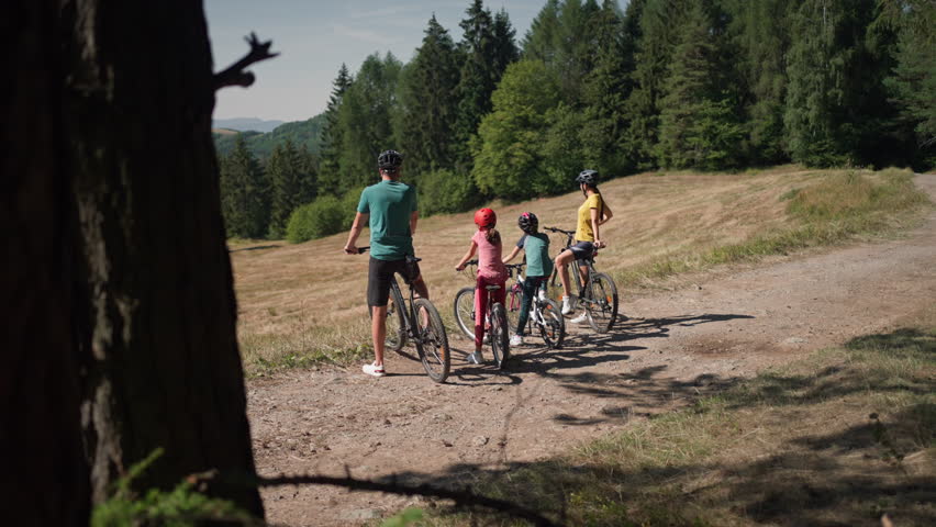 Family with children at bike trip, looking at view.