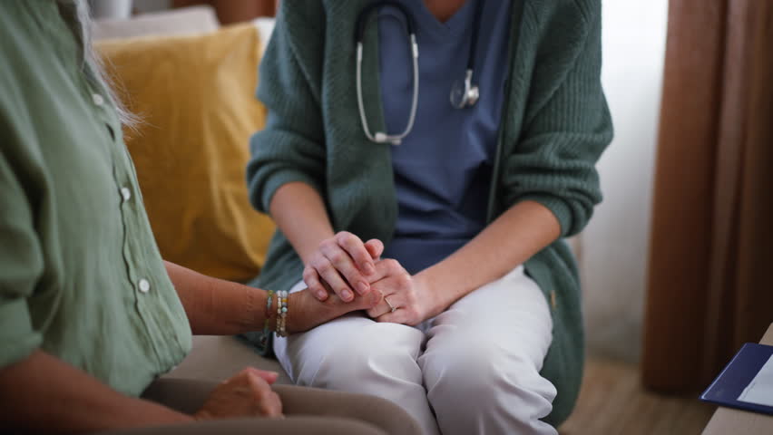 Nurse talking with senior woman, holding her hand and consoling her. | Shutterstock HD Video #1100682905