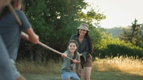 Young family with happy kids having fun together outdoors pulling rope in summer nature. - Powered by Shutterstock - Get 15% off with code: PIKWIZARD15