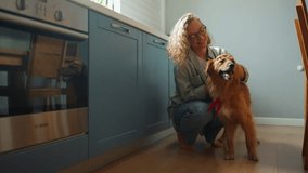 Cheerful curly haired woman stroking a dog in the kitchen at home - Powered by Shutterstock - Get 15% off with code: PIKWIZARD15