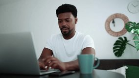 Positive African man talking by video call on laptop while sitting at home