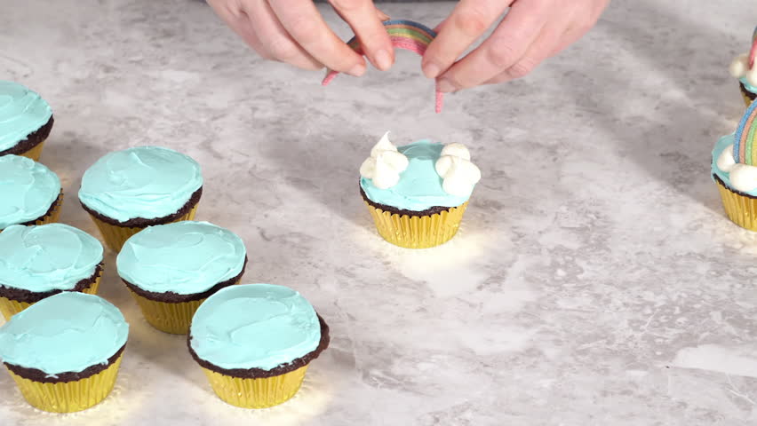 Decorating chocolate cupcakes with buttercream frosting and rainbow candy.