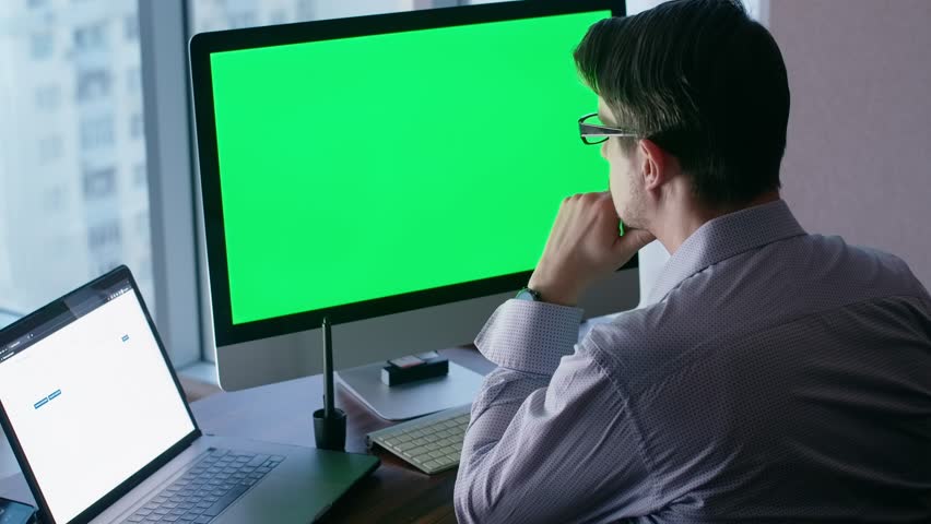 Man in office, sitting in front of a computer and analyzing stock rates. White color worker working with diagrams on the screen. Green screen for adding text.	 Royalty-Free Stock Footage #1100686853