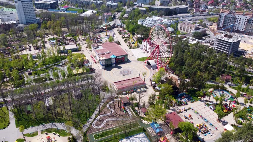Aerial arc right to left view on Ferris wheel in Kharkiv city amusement Central Park. Attractions in recreation entertainment area in spring