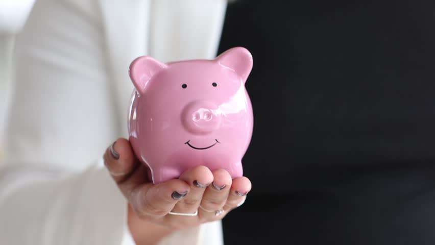 A business woman showing a piggy bank in her hand.
