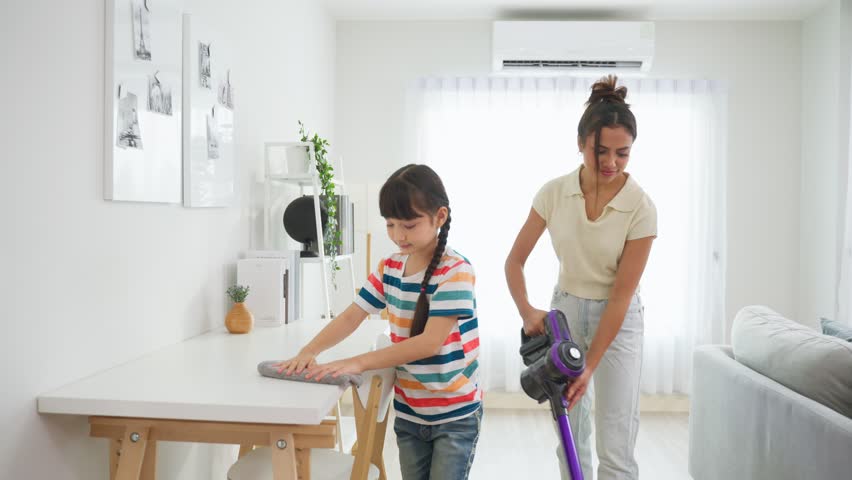 Caucasian beautiful mother cleaning house with young kid daughter. Attractive beautiful mom teaching adorable girl child vacuuming messy dirty floor for housekeeping housework and chores in house. | Shutterstock HD Video #1100690117