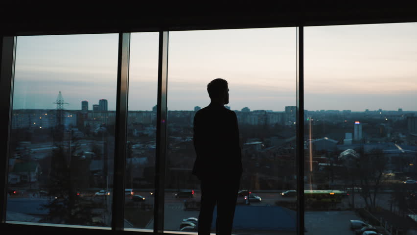 Back View of the Businessman wearing a Black Suit Standing in His Modern Office, Contemplating Future Deal, Looking out of the Window. Business District Panoramic Window View Royalty-Free Stock Footage #1100690819
