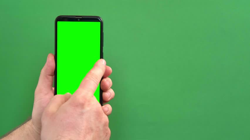 Young man hand use smartphone with green screen on green background. Gestures pack. Male hand touching, clicking, tapping swiping on black phone chromakey display. Close up Device. Modern Technology | Shutterstock HD Video #1100692783