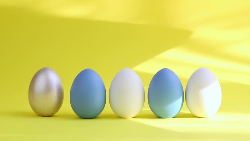 Egg are rolling on the yelloy background, knock each other. Easter colorful eggs isolated on yelloy background with hard shadow. Happy Easter card. Minimal easter concept. | Shutterstock HD Video #1100696853