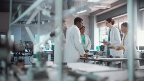 Dynamic Shot of Group of Young Multiethnic Lab Specialists Working as a Team to Analyse Blueprints and Digital Components Using Laptop Computer and Tablet. Professional Scientists Brainstorming - Powered by Shutterstock - Get 15% off with code: PIKWIZARD15