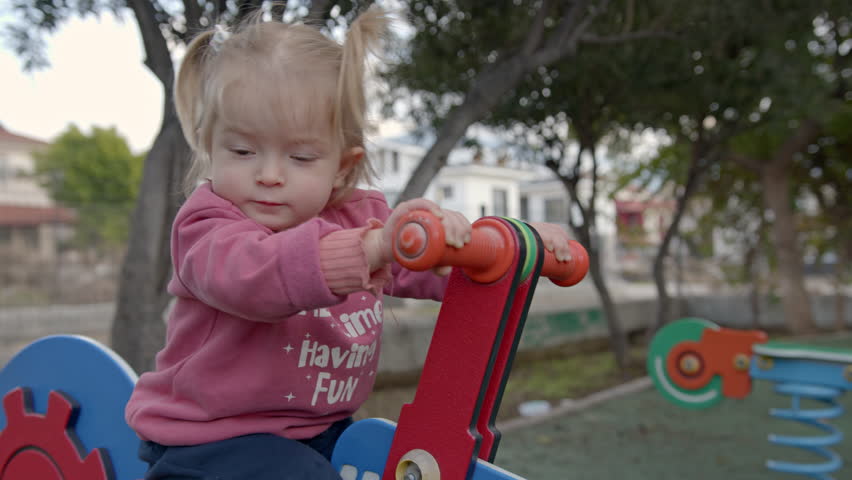 Portrait of little girl on a spring rider rides on the playground. Toddler playing on the playground.