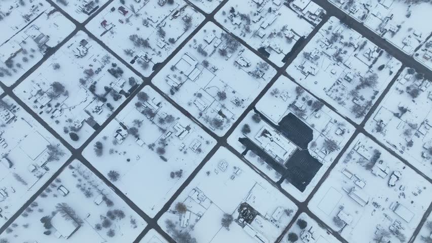 Aerial winter rural town church and school Utah. Aerial point of view. Winter storm and blizzard drops fresh white snow. Seasonal rural farm community. Homes, barns, farms, under white.